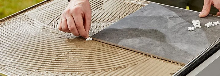 Person verlegt Fliesen auf einer Konstruktion